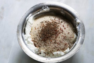 Greek yogurt with sugar, cardamom and saffron in a small steel bowl.