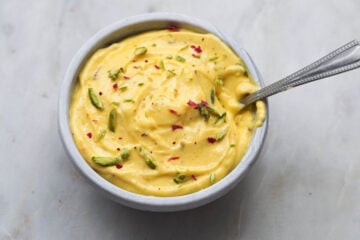 Kesar pista greek yogurt shrikhand in a bowl with a spoon.