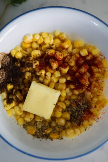 Coen in white bowl with red chilli powder, chaat masala and butter