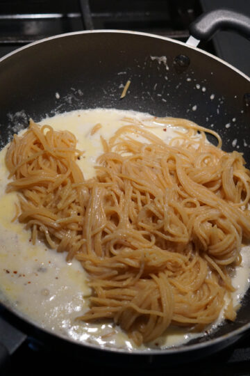 Spaghetti added to spicy cheese sauce