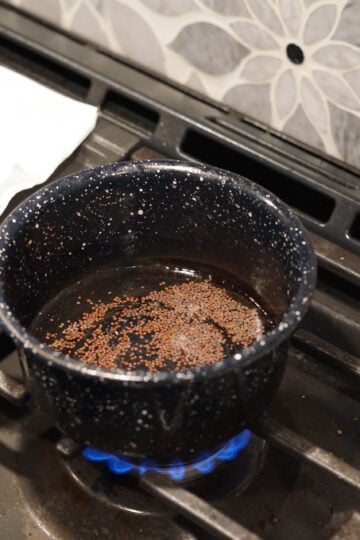 Mustard seeds in pan in heated oil.