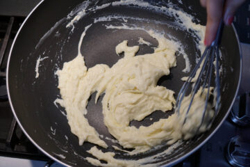 Cookies and cream milk burfi cooked in a pan on stove.