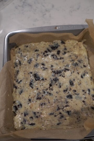 Cookies and cream burfi spread in parchment lined pan.
