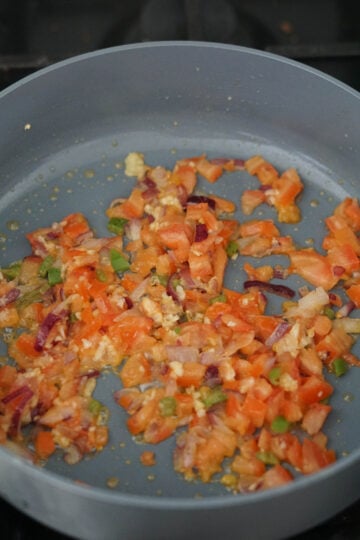 tomatoes onions peppers cooking in gray pan
