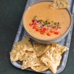 Tandoori queso in a bowl with corn chips in a steel tray