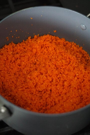 Shredded carrots in a non stick pan with vegan ghee or vegan butter.