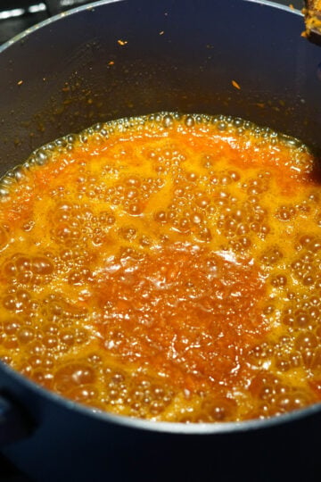 Halwa mixture is bought to a boil in pan on stove.