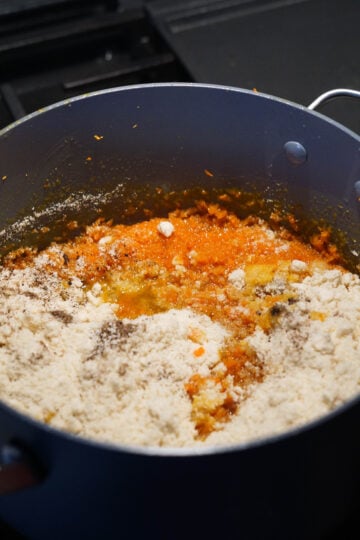 Almond flour added to carrot halwa mixture in pan.