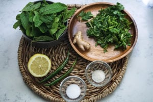 Mint pudina chutney ingredients in bowls on a bamboo plate