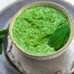 Mint chutney in a bowl with a mint leaf on top