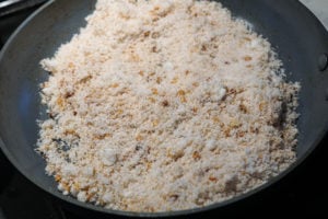 Dessicated coconut and dal roasting in a gray pan