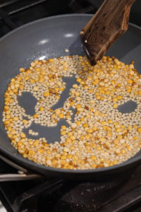 Urad dal and chana dal in a pan with oil being roasted.