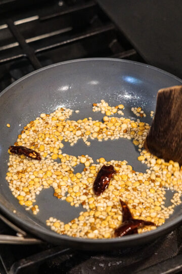 Red chillies added to pan with oil, urad dal and chana dal.
