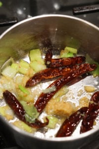 Red chillies added to oil in pot.