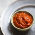 Momo chutney in a green bowl on a gray plate.