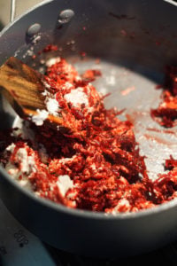 Cardamom, milk powder and sugar added to shredded beets in a pot.