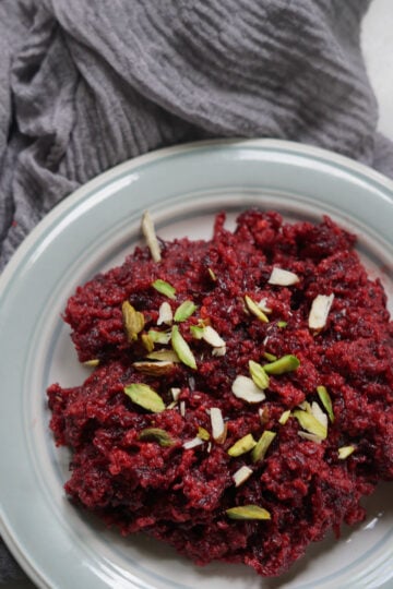 beetroot halwa on a plate with pistachios garnished on top