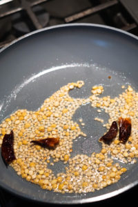 Urad dal and red chillies roasting in a pan