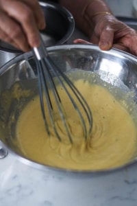 Whisking together ingredients for besan chutney in a steel bowl.