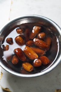 Dates soaking in warm wtaer in a steel bowl.