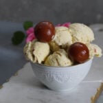 Gulab jamun ice cream with gulab jamuns in an ice cream bowl with rose petals o