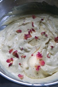 Gulab jamun ice cream mixture in a steel bowl with rose petal garnish.