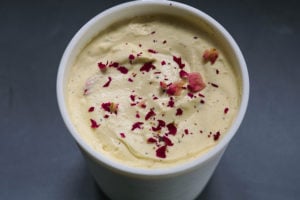 Gulab jamun ice cream mixture in a freezer safe container with rose petal garnish.