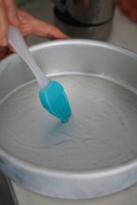 Oiling a steel pan with a brush.