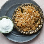 Sabudana khichdi in an ornate gold plate with a smaller bowl of yogurt to the side.