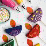 Diwali Diya Cake Pops with sprinkles and piping bags to the corner.