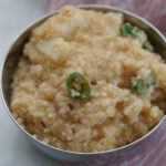Moraiyo khichdi in a steel bowl on a pink cloth, garnished with green chillies.