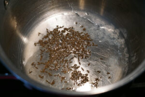Oil heated in a pot with cumin seeds
