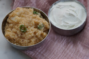 Moraiyo khichi served with a bowl of yogurt to the side.