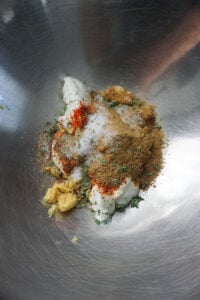 Greek yogurt and masalas in a steel bowl.