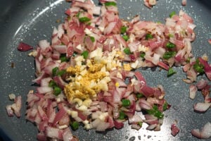 Garlic added to onions and green chillies to saute in a pan.