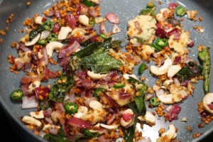 Quinoa upma ingredients in a pan, sauteeing in oil.