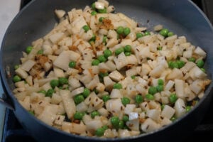 Potatoes and peas added to pan for samosa filling.