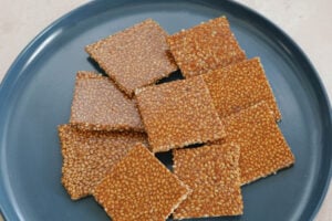 Square chikki bar pieces laying on a blue plate.