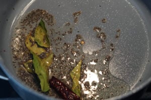 Oil heated in a pan with mustard seeds, red chillies, curry leaves and hing.