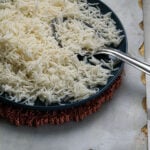Indian basmati rice on a blue plate with a steel serving spoon.