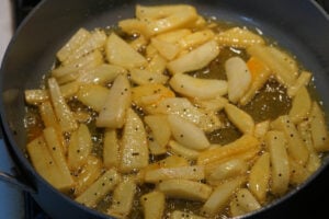 Turmeric and salt added and mixed with potatoes in pan.