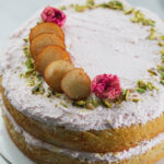 Gulab Jamun cake decorated with pistaschios, roses and gulab jamuns.