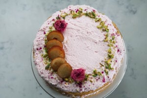 Gulab jamun cake decorated with crushed pistachios, gulab jamun and roses.