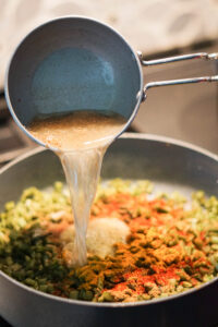 Pouring tadka on spices on shaak.