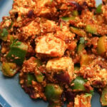 Paneer sabzi with bell peppers on a blue plate.