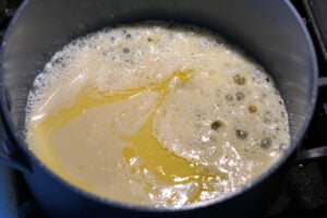 Ghee and condensed milk in pan.