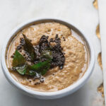 Peanut chutney with tadka on top in a smal gray bowl.