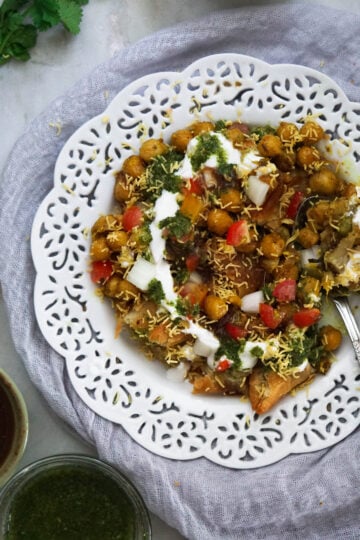 Prepared samosa chaat in a white lace trim plate.