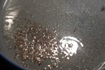 Heated oil in a pan with mustard seeds.
