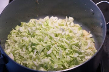 Chopped cabbage added to pan.